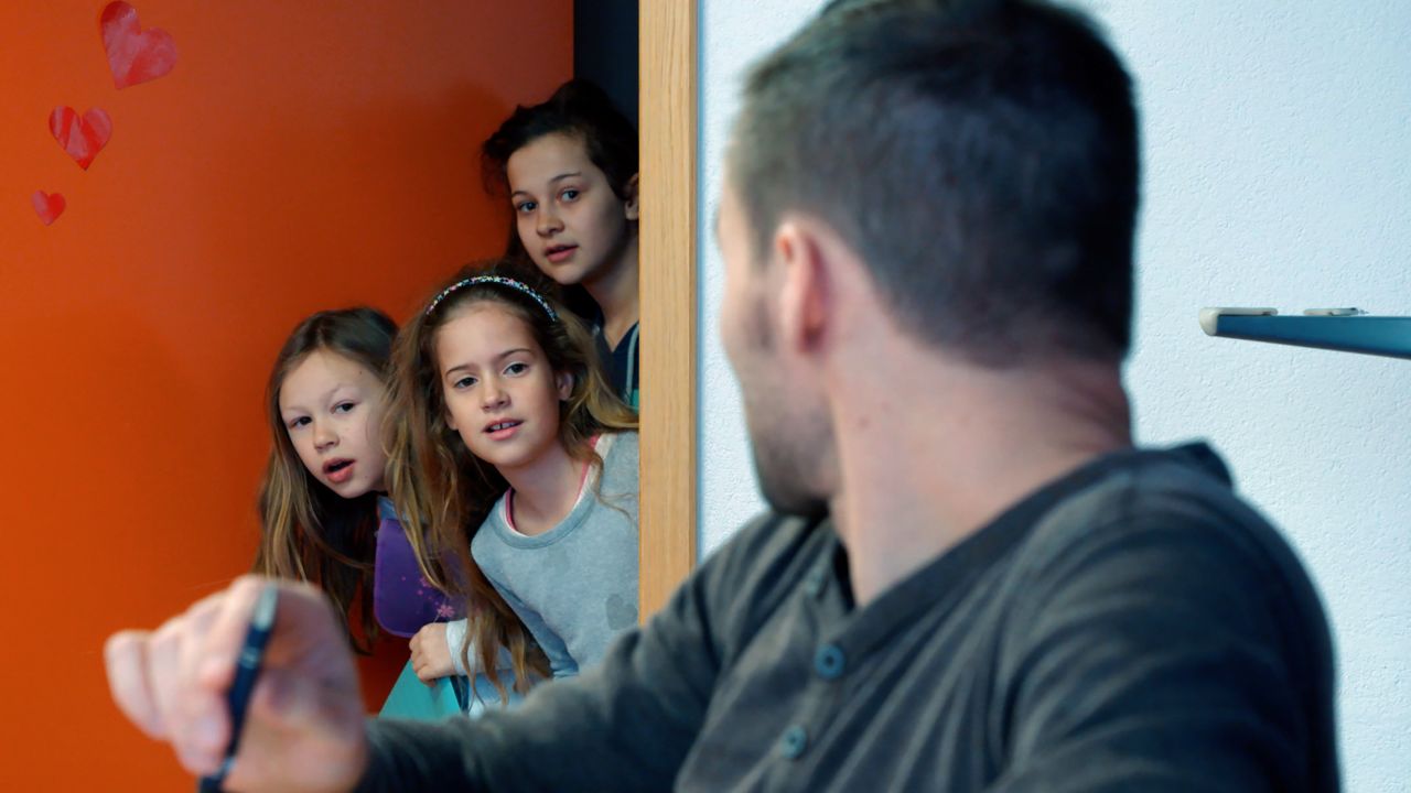 Schüler:innen strecken ihren Kopf durch die Türe zum Lehrer